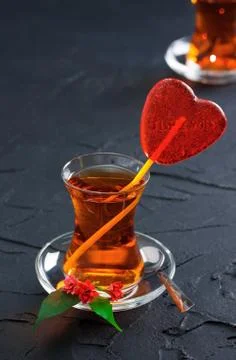 Glass cup with a tea and candy heart Stock Photos