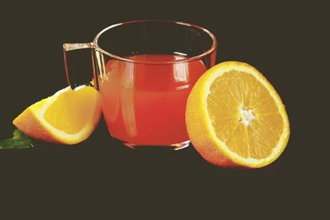 Glass cup with a vibrant array of fresh fruit, including a juicy half of an oran 写真素材