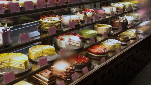 Glass display case with a large variety of cakes in a cafe that sells cakes by Stock Footage 277911051