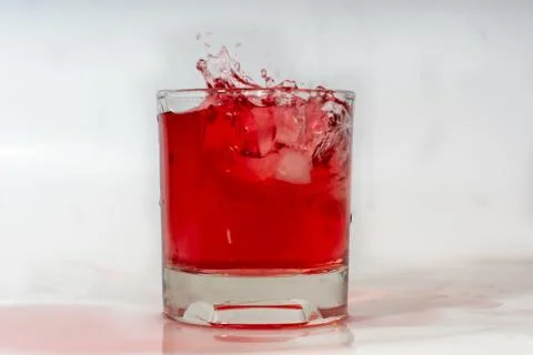 A glass with a drink and ice. Ice falling in Stock Photos