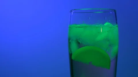 Glass with a drink on a colorful blue background Stock Footage