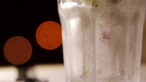 Glass with drink, ice, mint and berries on a blurry background 库存影片 73997901