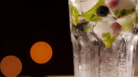 Glass with drink, ice, mint and berries on a blurry background Stock Footage 73998124