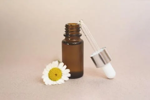 A glass dropper bottle on the beige background. Stock Photos