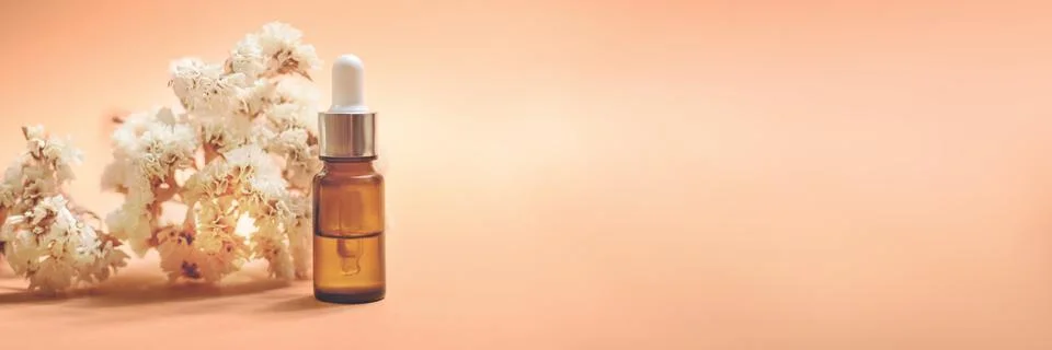 A glass dropper bottle on the orange background. Stock Photos