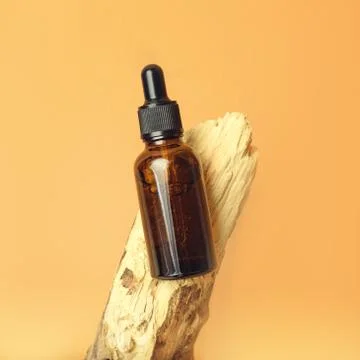 A glass dropper bottle on the orange background. Stock Photos