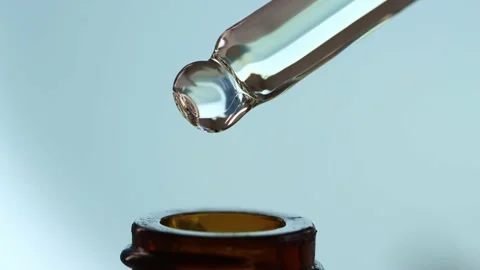 Glass dropper macro with falling drops of oil, serum, peptide Stock Footage 232586699