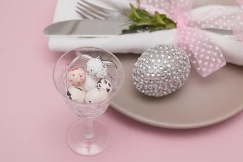 Glass with Easter eggs on the background of plates and cutlery. Variative foc Stock Photos