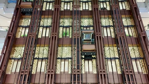 Glass elevator moving up luxury Shanghai mall atrium with golden geometric Stock Footage 323899427