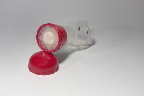 Glass empty pepper mill with red top, laying on its side Stock Photos