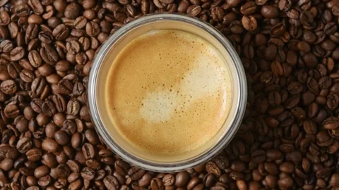 Glass espresso cup rotates on roasted coffee beans in top view for cafe and Stock Footage 345222635
