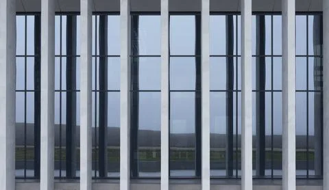 Glass facade framed by vertical columns reveals interior and distant landscap Foto stock