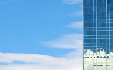 Glass facade of office building reflects sky and clouds Foto stock