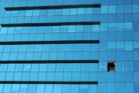 The glass facade of a skyscraper with a mirror reflection of sky windows Stock Photos