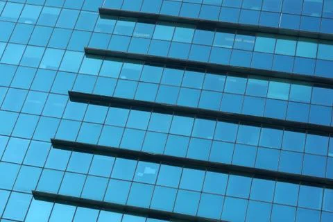 The glass facade of a skyscraper with a mirror reflection of sky windows Stock Photos