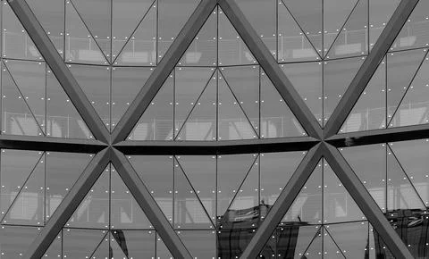 Glass facade with triangular grid pattern and structural beams. Architectural Stock Photos