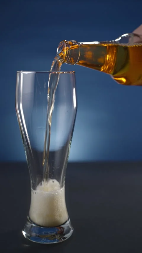 A glass is filled with beer from a bottle. vertical Stock Footage 295705607