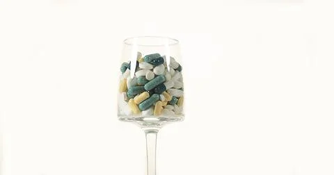 Glass filled with Capsules Exploding against White Background 스톡 사진