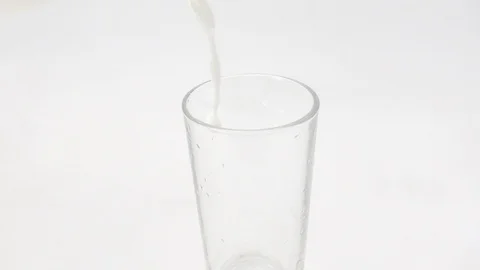 A glass is filled with milk from a bottle Stock Footage 128374638