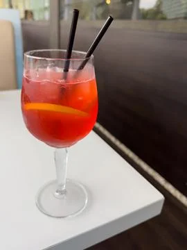 A glass filled with red liquid featuring two straws for sipping Stock Photos