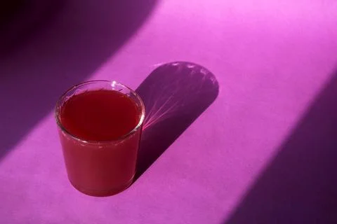 A glass of fresh compote on a colored background. Hard light from the window. Stock Photos