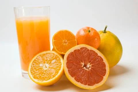 Glass of fruit juice and fresh citrus fruit Stock Photos