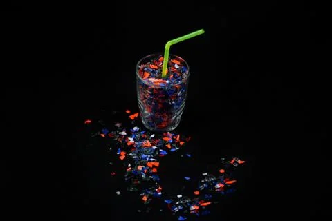 Glass full of crushed plastic pieces. Stock Photos