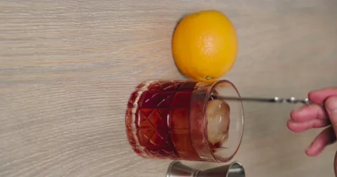 Glass full of negroni with ice while being stirred with a mixing spoon Stock Footage 156564248