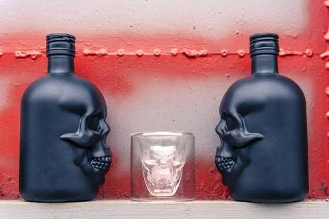 Glass gin bottles in the shape of a human skull and a glass stack Stock Photos