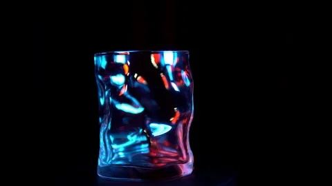 The glass goblet turns under a blue and red backlight on a black background Stock Footage 84145639