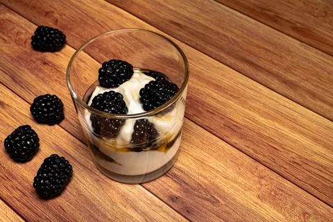 Glass with a homemade dessert with yogurt, blackberries and honey. Stock Photos