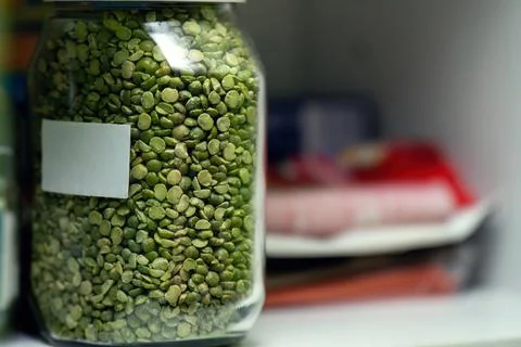 Glass jar filled with dry split green peas sits on a shelf. The jar features  Stock Photos