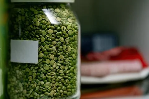 Glass jar filled with dry split green peas sits on a shelf. The jar features  Stock Photos