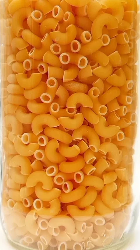 A Glass Jar Filled With Elbow Macaroni Pasta Rotating on White Background,  库存影片 334367945