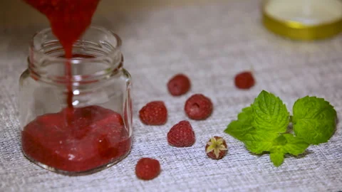 A glass jar is filled with raspberry jam. Home canning. Stock Footage 246705212