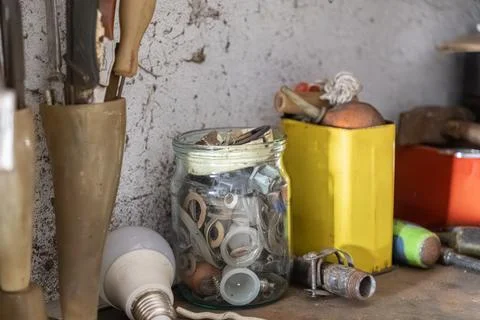 A glass jar filled with small hardware parts sits on a cluttered workshop Stock-Fotos