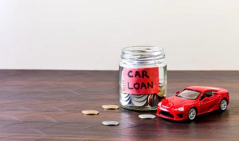 A glass jar full of coins placed with a toy car. Car loan is labeled on the jar Stock Photos