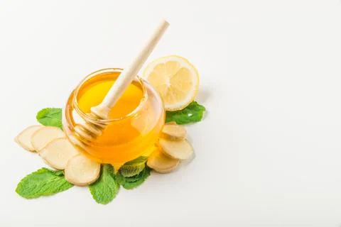 Glass jar of honey with ginger, mint and lemon isolated on a white background Stock Photos