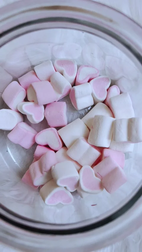Glass jar with many marshmallows in the form of hearts on white background. Video stock 273816983