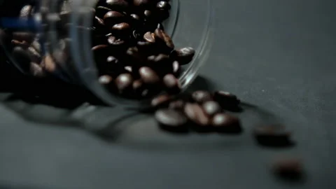 Glass jar of roasted coffee beans lying down on black surface Stock Footage 162596817