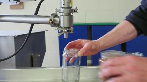 Glass jars being filled with sauce and capped by hand at a small artisan fo.. Stock Footage 308879095