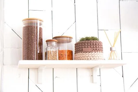 Glass jars with cereals are on a shelf and a crocheted pot of microgreens in  Stock Photos