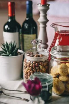 Glass jars with hazelnuts, biscuits and mors, flower pot and bottle of wine Stock Photos