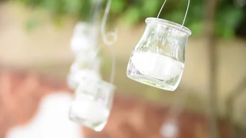 Glass jars on a string decorate a beautiful garden. Wedding day decoration Stock Footage 151409783