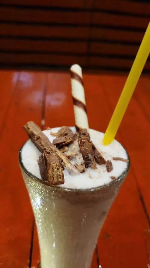 A glass of Kit Kat Milk Shake with a small black lamp Stock Footage 286311155