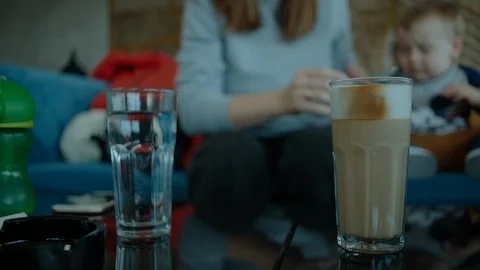 Glass of latte on a table in a cafe. Mom with a child drinks coffee Vídeo Stock 127051838