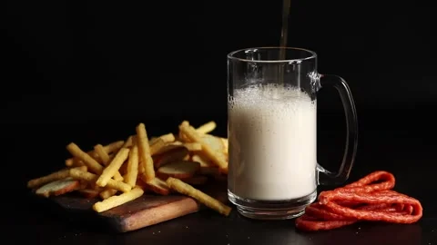 Glass with light beer and snacks on a dark background Stock Footage 297207765