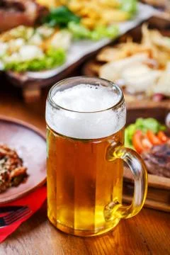 A glass of light beer on the background of a table with snacks. Stock Photos