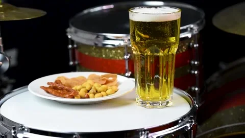 Glass of light beer with salty snacks on professional drum set closeup Stock Footage 149010341
