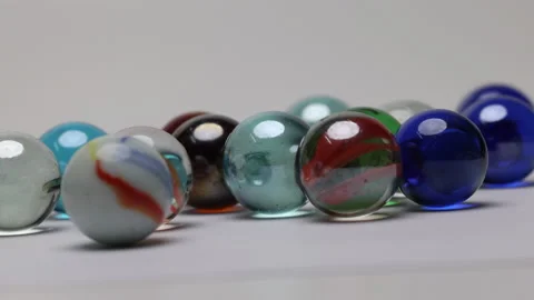 Glass marble balls playing rolling hitting clashing on white background  Stock Footage 182682897